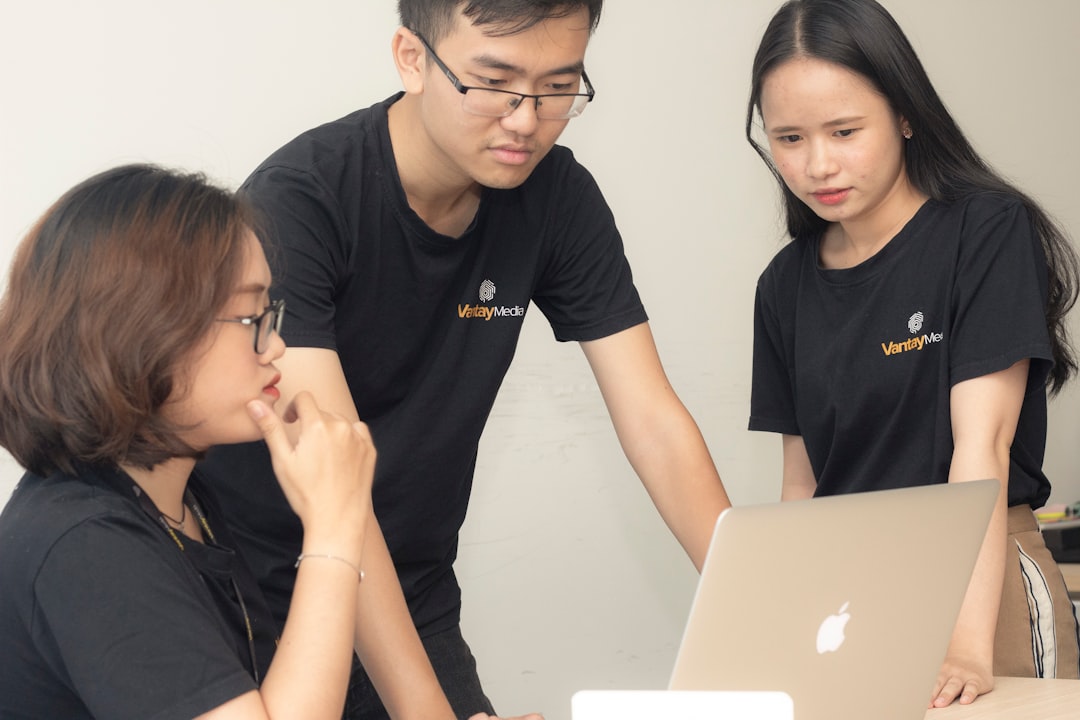 ai seo agency — two women and one man looking onto MacBook screen