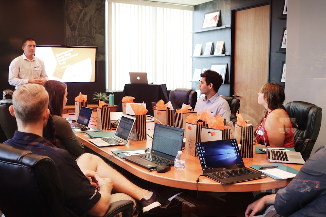 ai seo agency — man standing in front of people sitting beside table with laptop computers
