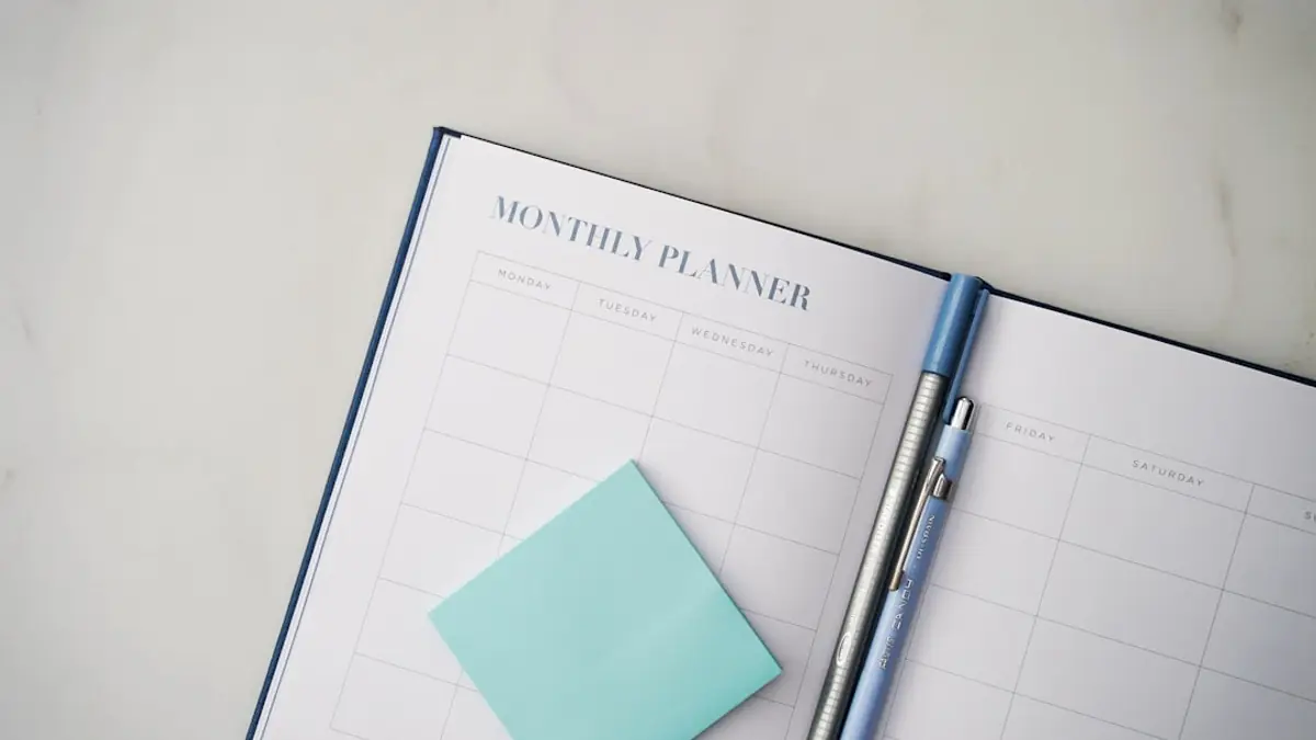 An open paper planner on a desk with a pen resting on the page.