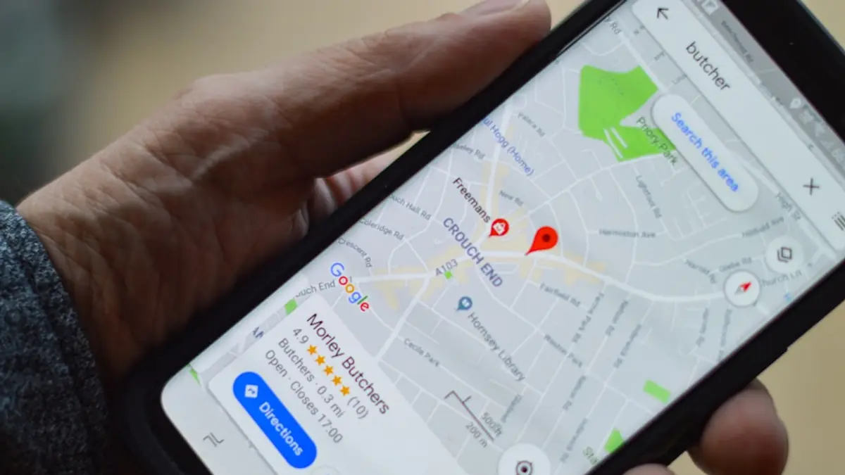 A hand holding a phone showing a local business result on Google Maps.