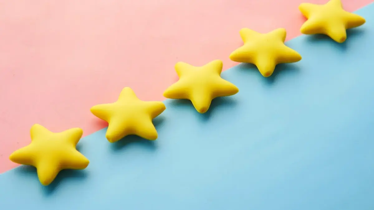 Five yellow star shapes arranged in a row on a coloured surface.